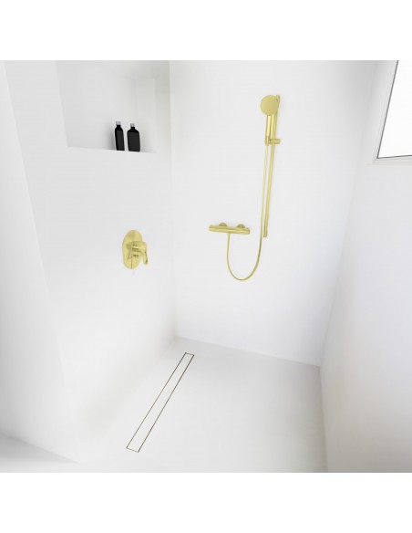 Open walk-in shower, surrounded by light-colored microcement floor and walls, with fittings in Gold - tiled cover side
