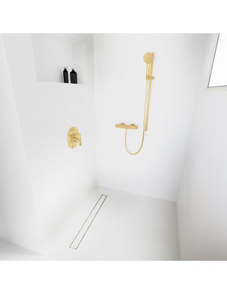 Open walk-in shower, surrounded by light-colored microcement floor and walls, with fittings in Brass