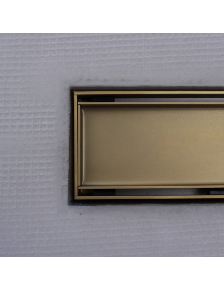 Close up on integrated Gold linear drain with matching Reversible cover